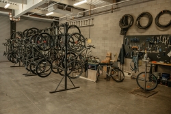 A bike workshop area where multiple bikes are hung up on a bike rack.