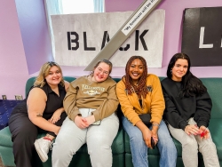 Four people sitting next to each other on a couch smiling.