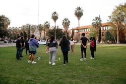 A group of people standing together in a circle on a grass field.