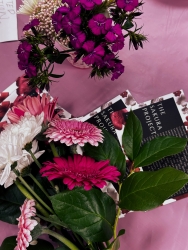 Flowers placed on a table that is covered in pink cloth. Informational cards about the Sakura Project lay underneath the flowers. 