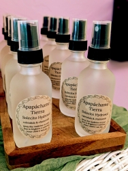 Various spray bottles lined up in a wooden holder. The bottles contain mixtures of calendula and chamomile.