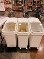 three plastic bins with wheels are seen in Campus Pantry holding food for distribution