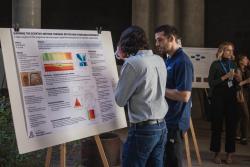 Two people looking at a poster titled "Learning the scientific method through an evolving hydrologic experiment"