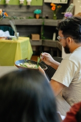 A person grabbing an herb from a brown bowl.