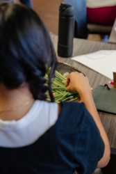 A person grabbing an herb from a brown bowl.