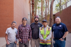 A group of 5 workers standing next to each other and smiling.
