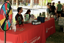 Two people sitting behind a table that is covered with outreach material and a red cloth.