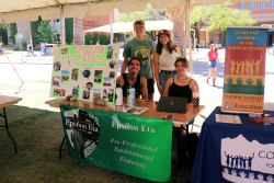 Four people smiling behind a table covered in outreach material.