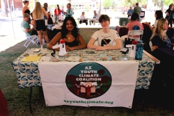 Two people smiling and sitting behind a table covered in outreach material.