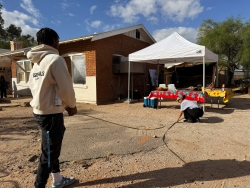 Two people holding a measuring tape in front of a house.