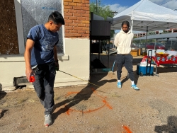 Two people holding a measuring tape in front of a house.