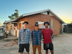 Three people smiling in front of a house.