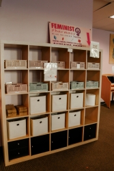 A large wooden cubby with multiple boxes that include hygiene products in it.