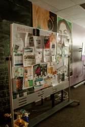 A large whiteboard that is covered in various hanging fliers. 