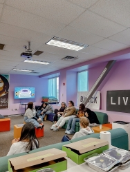 A group of people sitting together in a common area and talking to one another.