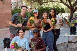 A group of people smiling and holding various types of flowers.