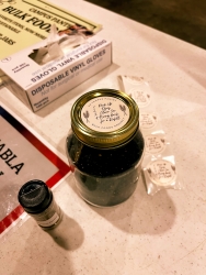 A jar next to a seasoning shaker. A sticker is placed on top of the jar lid. 