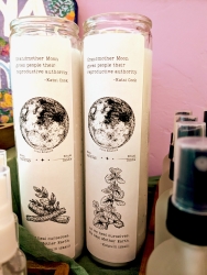 Two long white candles with a sticker on them.