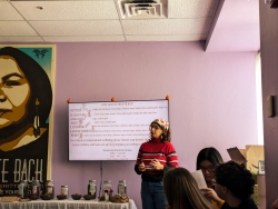 A person standing next to a television that is showcasing a presentation slide while the person presents to a group of people.