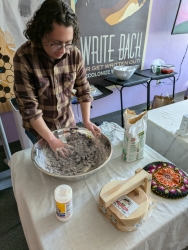 A person hand mixing tortilla paste in a large silver bowl.