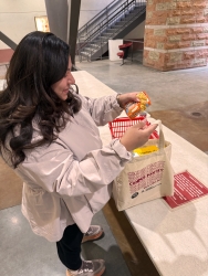 A person putting food into a reusable tote bag.