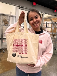 A person smiling and holding a reusable tote bag.