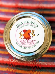 The top lid of a circular jar that has a sticker on it. The jar has a rose honey heart soother mix in it.