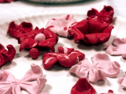 A plate that is filled with clay cherry blossoms. Some are made with light pink clay and others with dark pink clay.