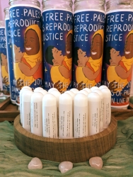 Multiple herbal nasal sprays on a circular wooden holder. Behind the holder is a line of candles.