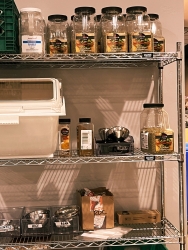 a storage rack with various plastic bins filled with seasoning.