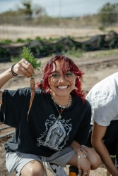 a person ina  field holding up a baby carrot they just pulled from the soil