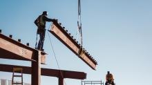 Construction workers lower a steel beam into place. 