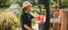 a student refills her water bottle at a water bottle refill station located in a community garden
