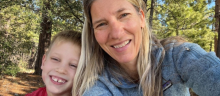Sabrina Helm and her son sit together in a wooded area smiling