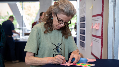A woman writes down ideas on a sticky-note at the Sustainability and Climate Action Plan Kick-off Event