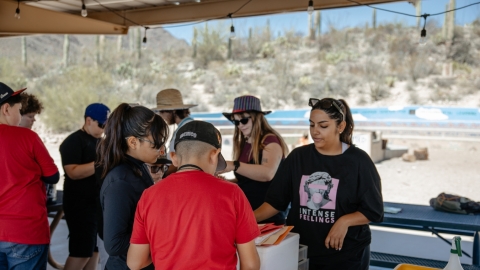 A group of students talking around a picnic table.