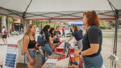 Visitor at tabling event talks to an educator. 