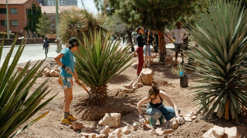 Two people creating a rain basin using large rocks