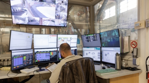A person sits at a computer, looking at systems' data and performance