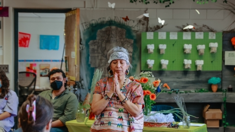 A person standing in front of a table with their hands together and their eyes closed.